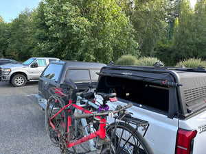 MOTU and bikes on Toyota Tacoma parked next to a Leer truck cap. 