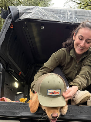 Dog and person under a MOTU hybrid truck cap, integrates a soft top canopy and exoskeleton gear rack on a Toyota Tacoma pickup. Weatherproof. 